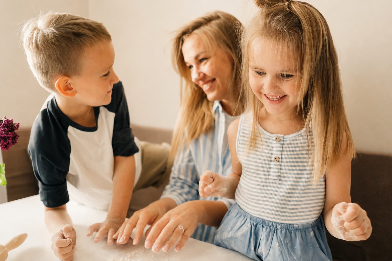 Mama in dva otroka skupaj kuhata v kuhinji ter preizkušata zabavne aktivnosti za otroke s karticami Vireos.